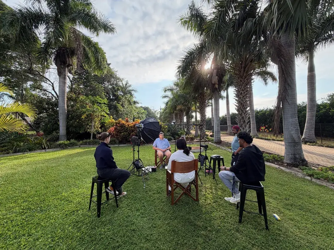 A ThinkStory crew filming an outdoor interview under the palms